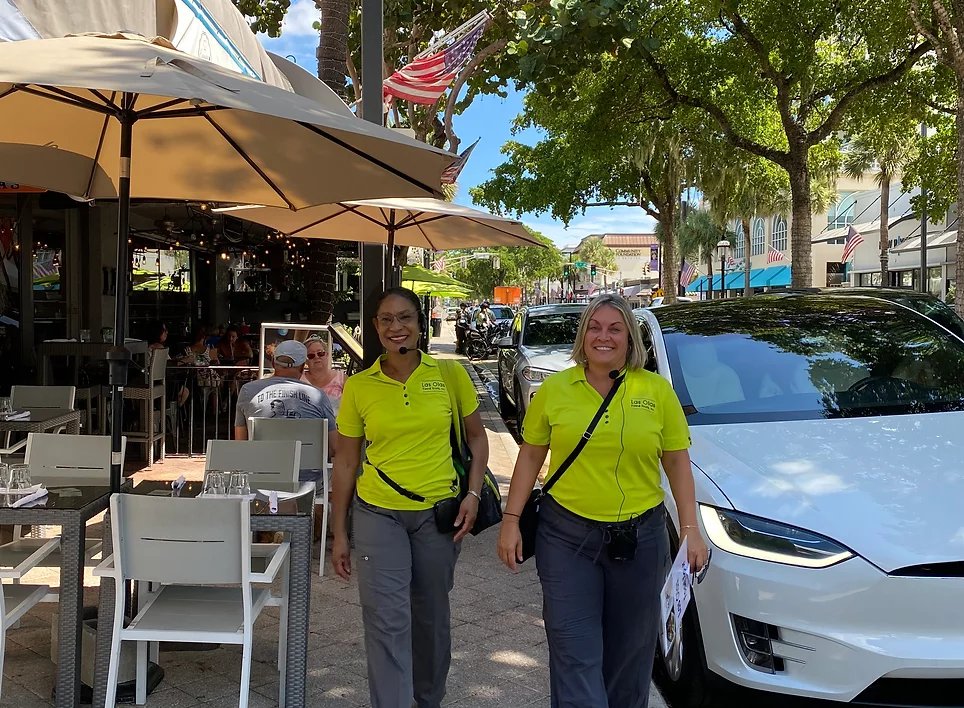 Two women in yellow shirts are walking down the street.